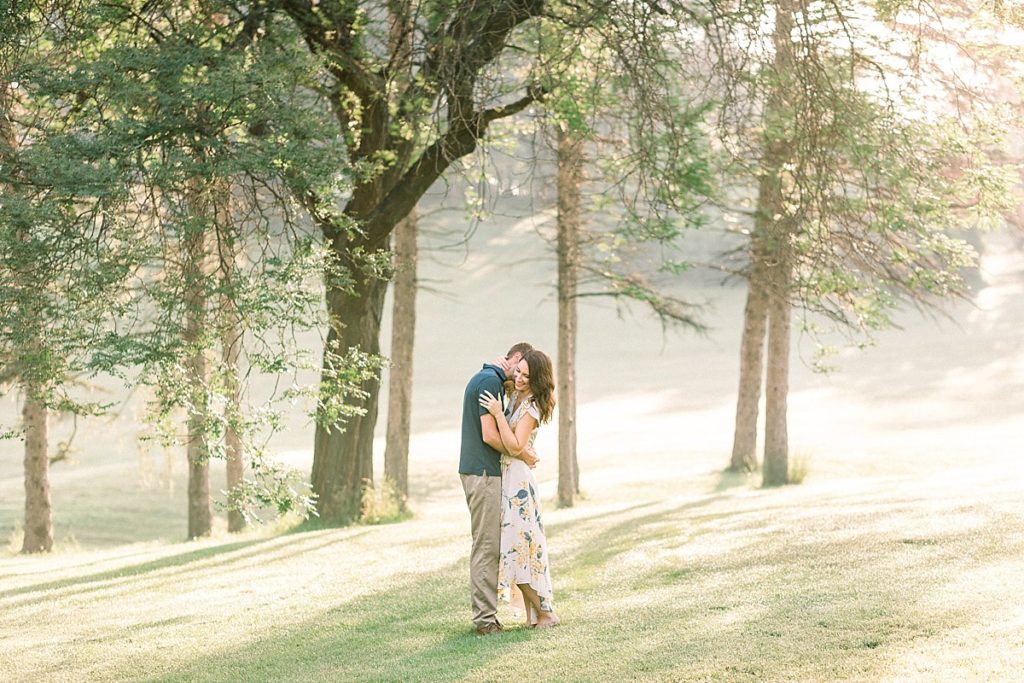 Couple in front of sun pouring through trees