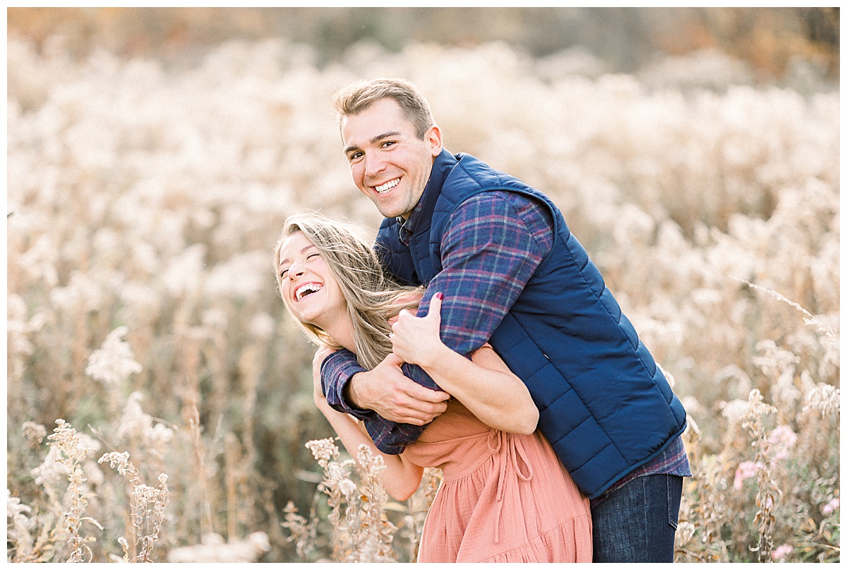 engaged couple laughing in field