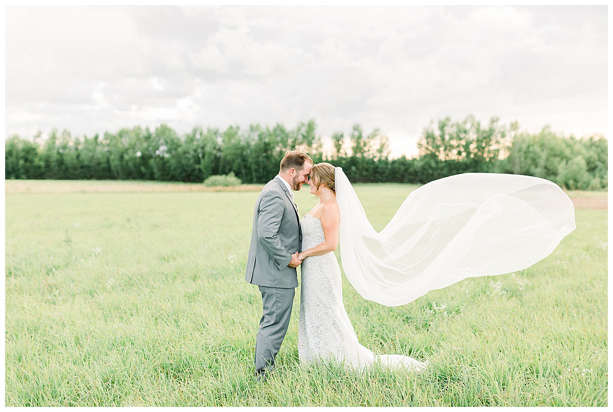 bride and groom holding hands in field