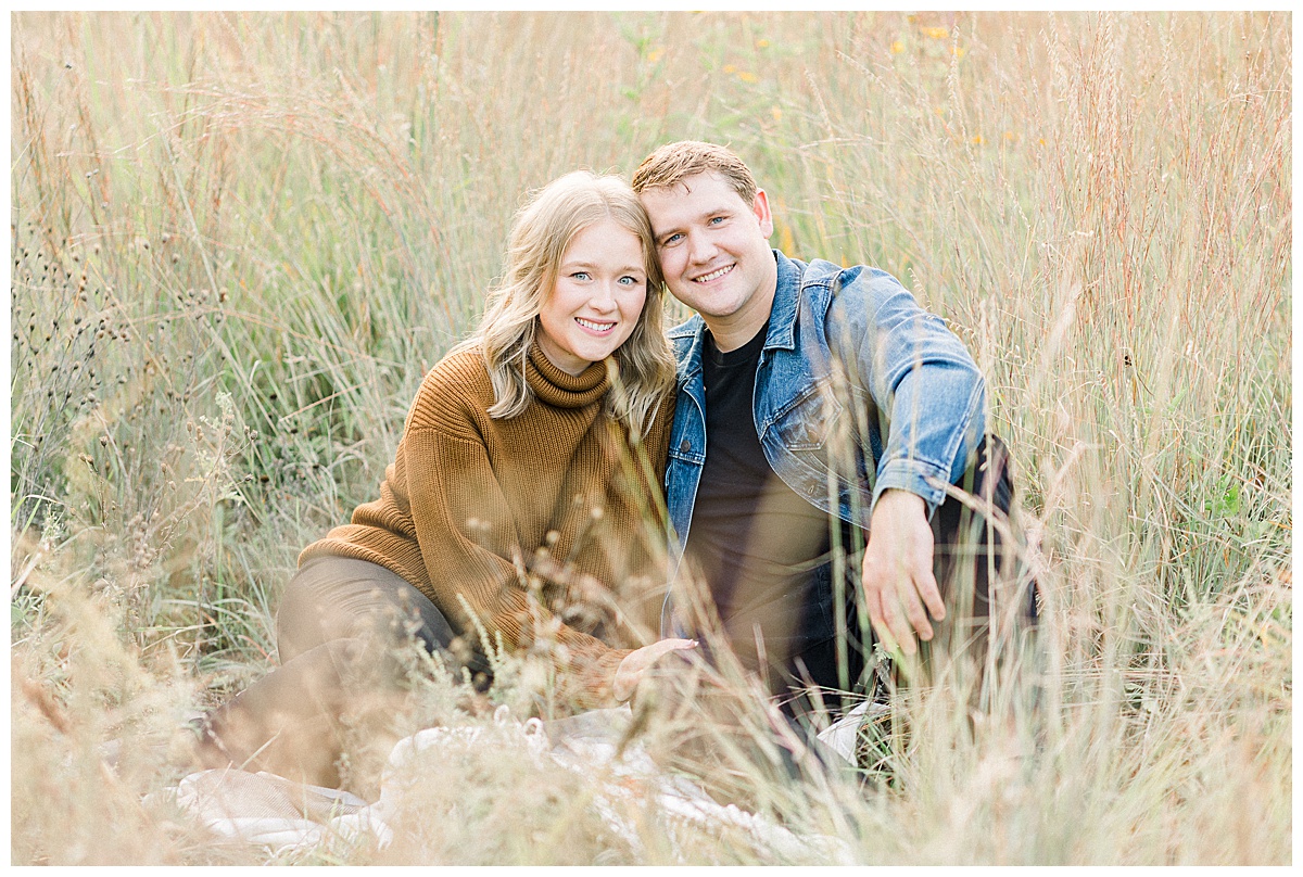 couple sitting in a field for photos