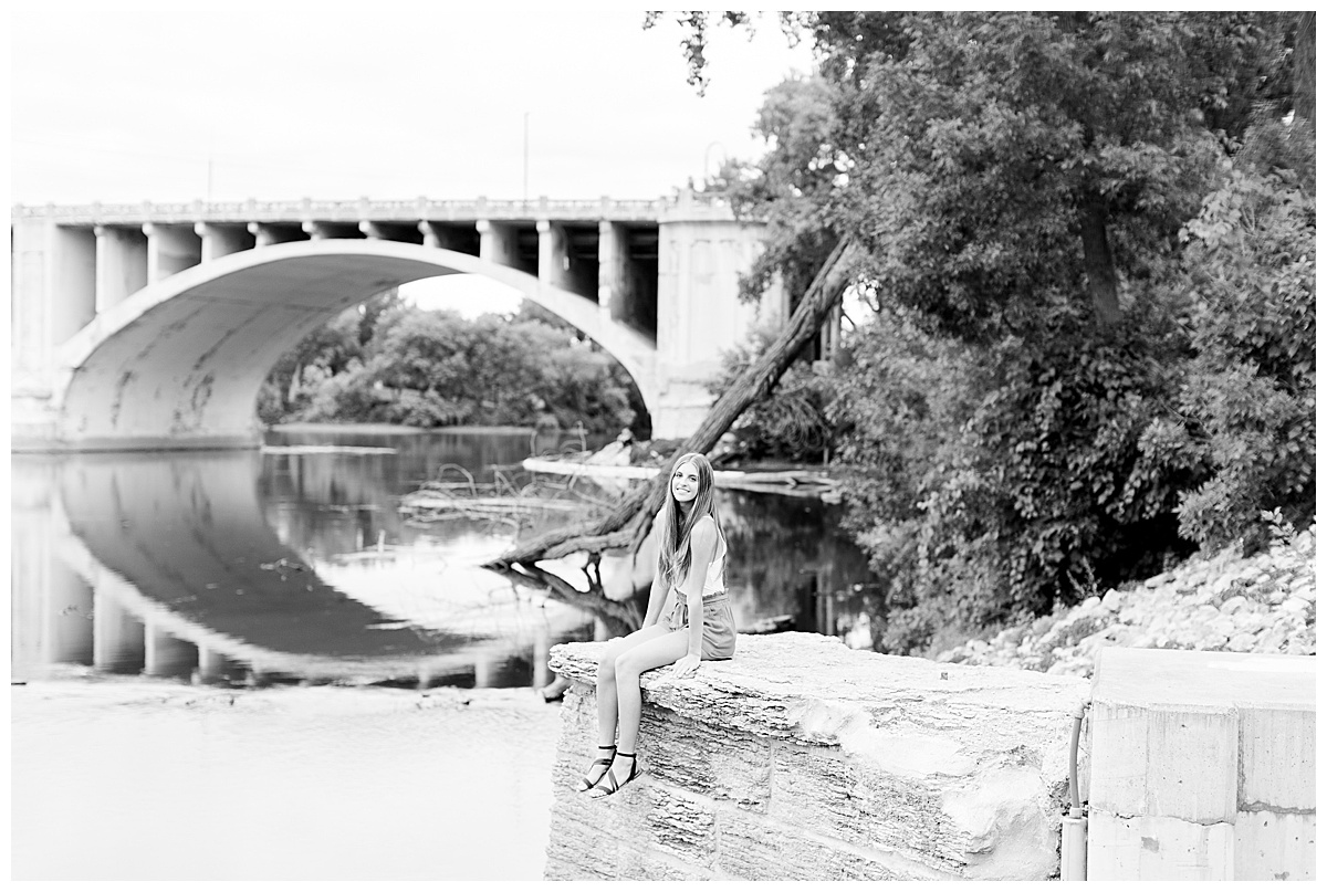 girl sitting by bridge for senior pictures