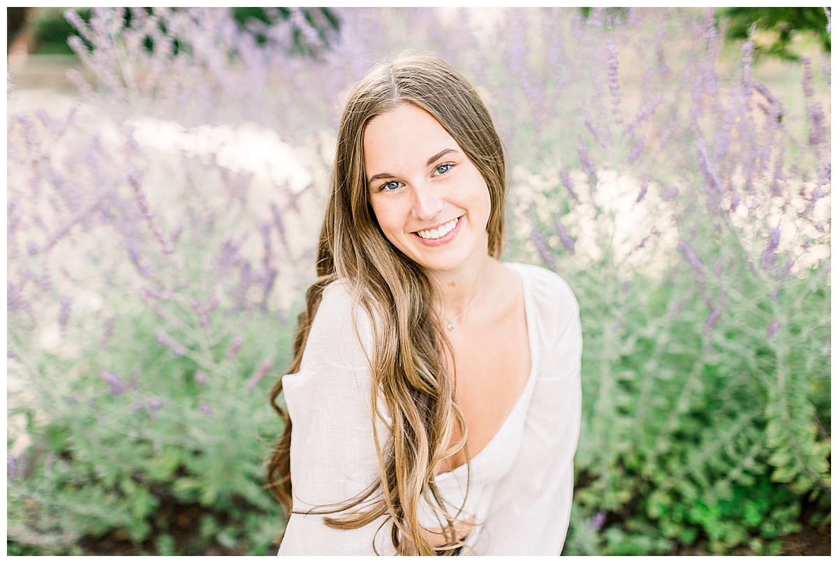girl smiling by lilacs for senior session