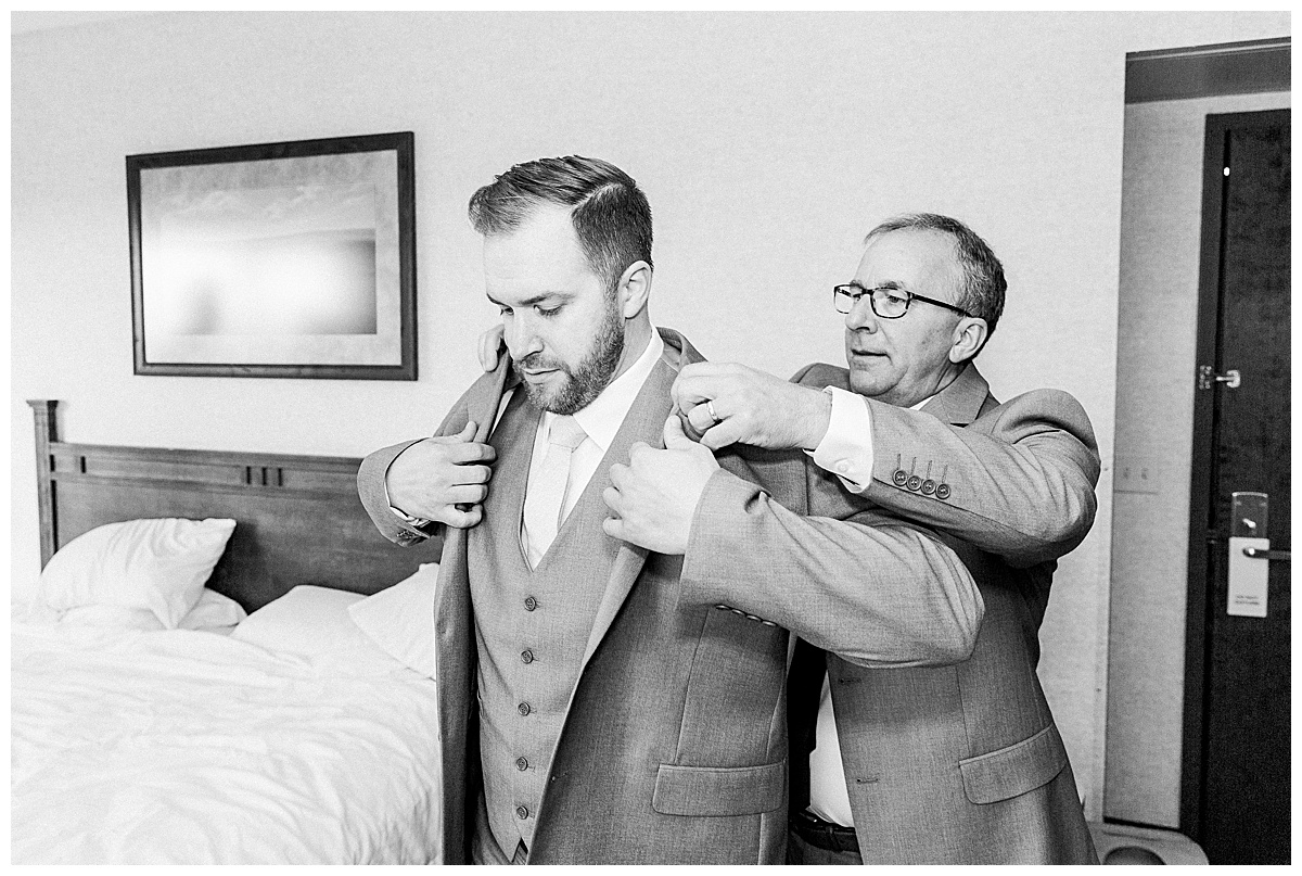 groom putting on suit jacket