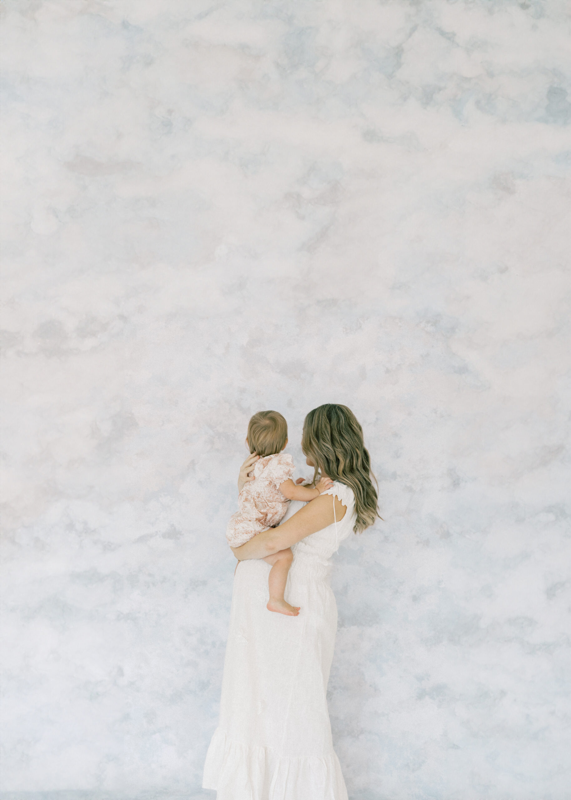 Pregnant mother and daughter in a light-filled studio during baby milestone photography session